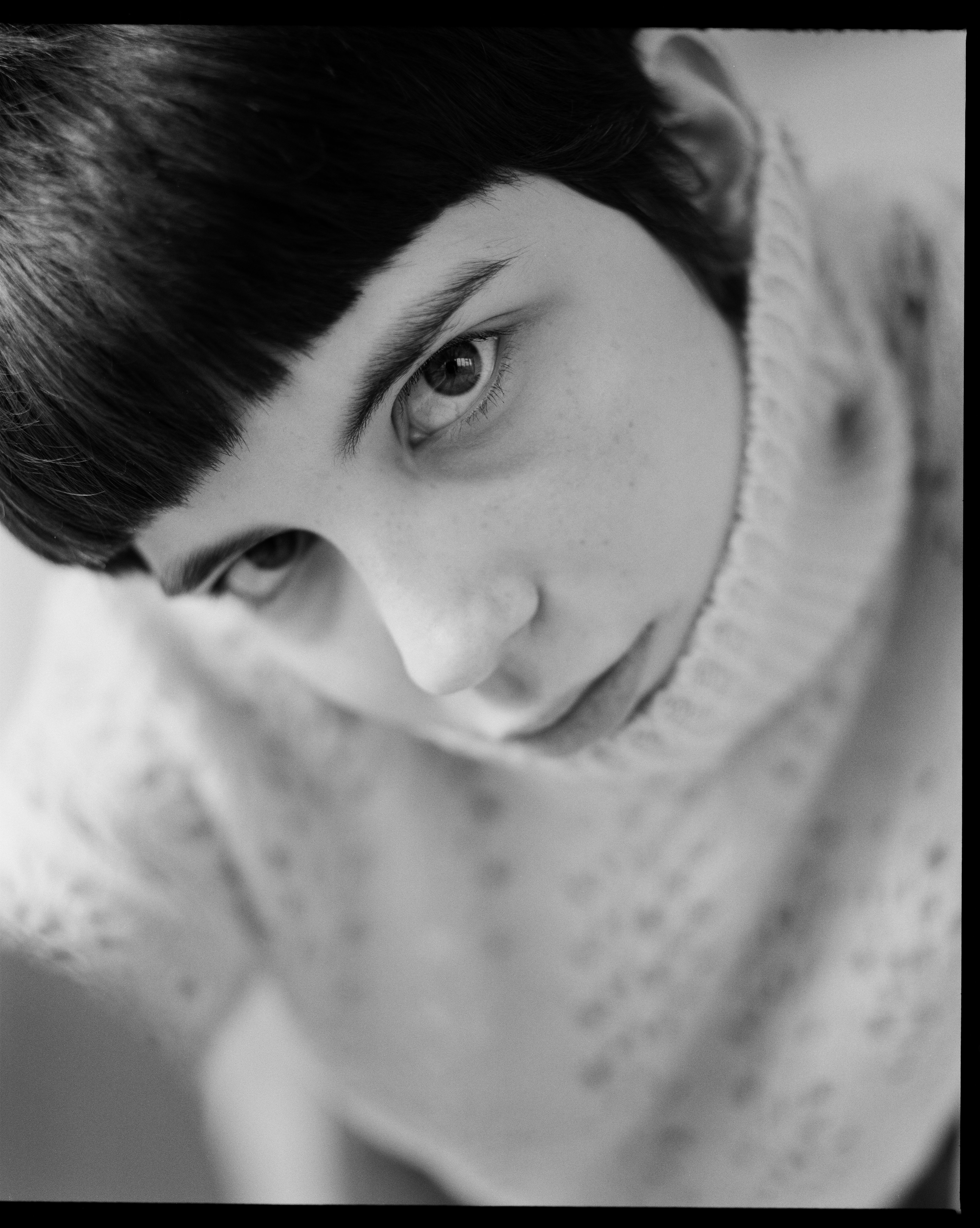 Black and white portrait of a woman with short hair, wearing a knit sweater and looking directly at the camera.