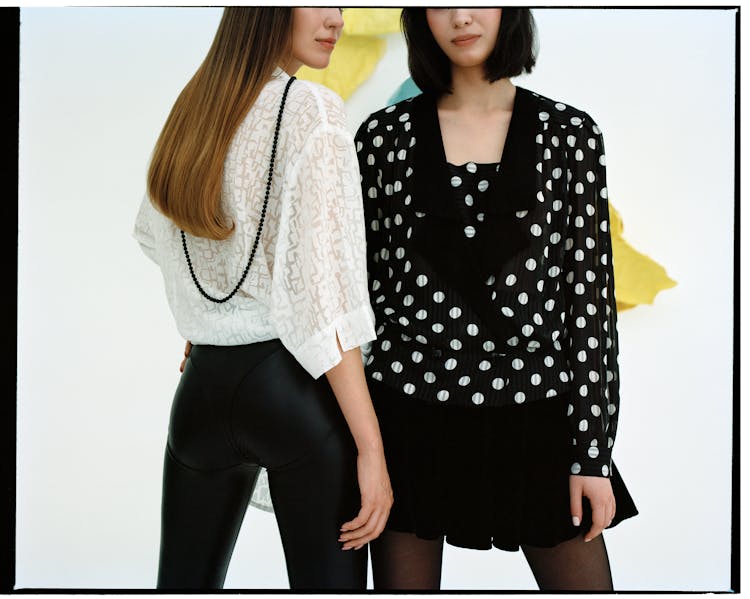 A Woman In Polka Dots Long Sleeves Standing Beside A Woman Looking Over Shoulder