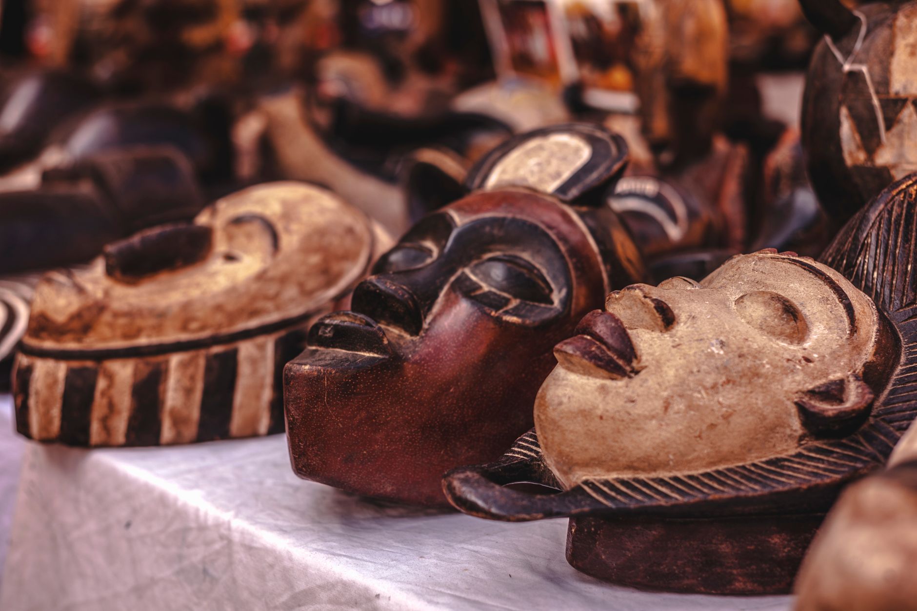 Carved wooden masks with intricate designs displayed at a vibrant market.