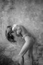 Black and White Photo of Shirtless Woman Hunching Over