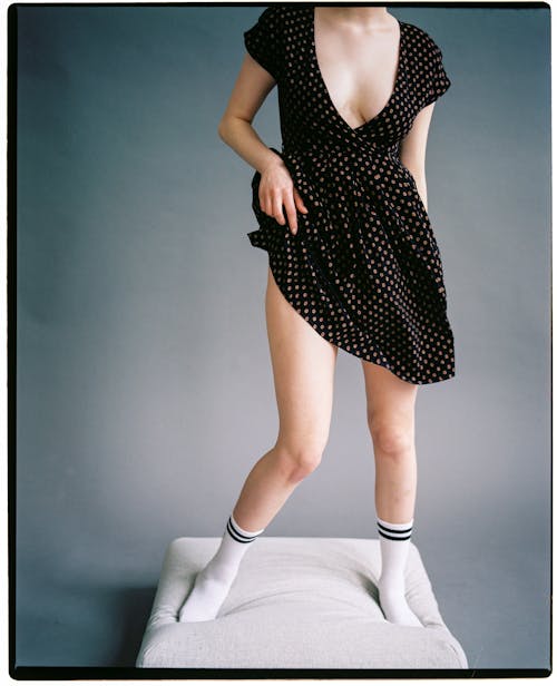 Woman in Polka Dot Dress and White Socks Standing on Pillow