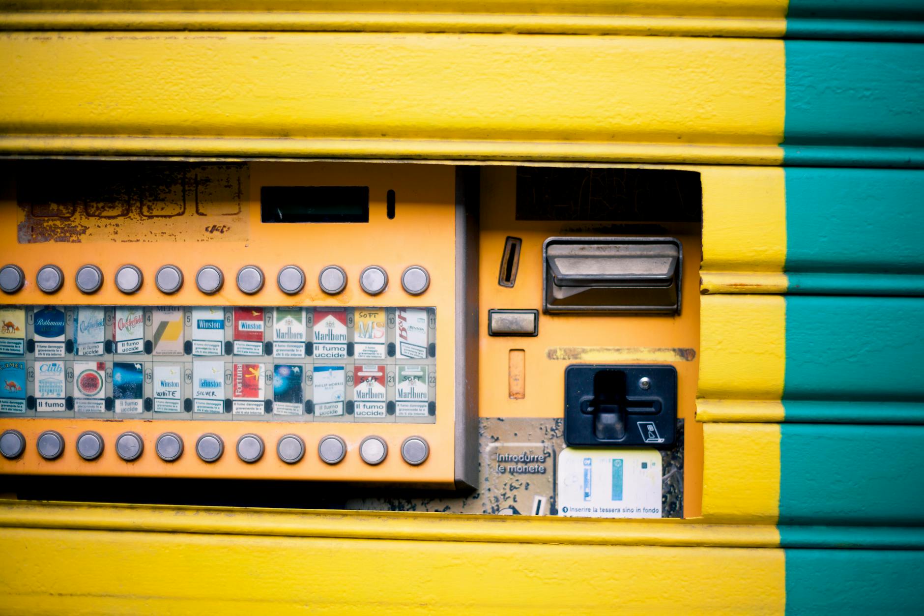 Detailed view of a vibrant yellow and green cigarette vending machine interface. The bold colors, selection buttons, and sturdy build echo the vibe and design of classic slot machines available for collectors.