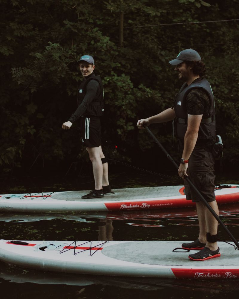 Dos personas remando en paddle surf en aguas tranquilas a primera hora