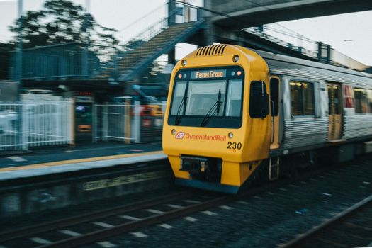 A Queensland Rail train departs Loganlea Station in Queensland, Australia, captured in motion.