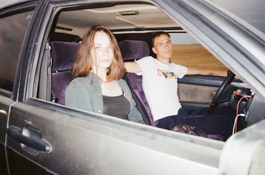 A young couple sits in a car on a road trip, evoking a sense of freedom and adventure.