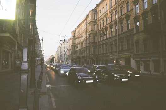 Busy urban street with moving cars and historic architecture under twilight.