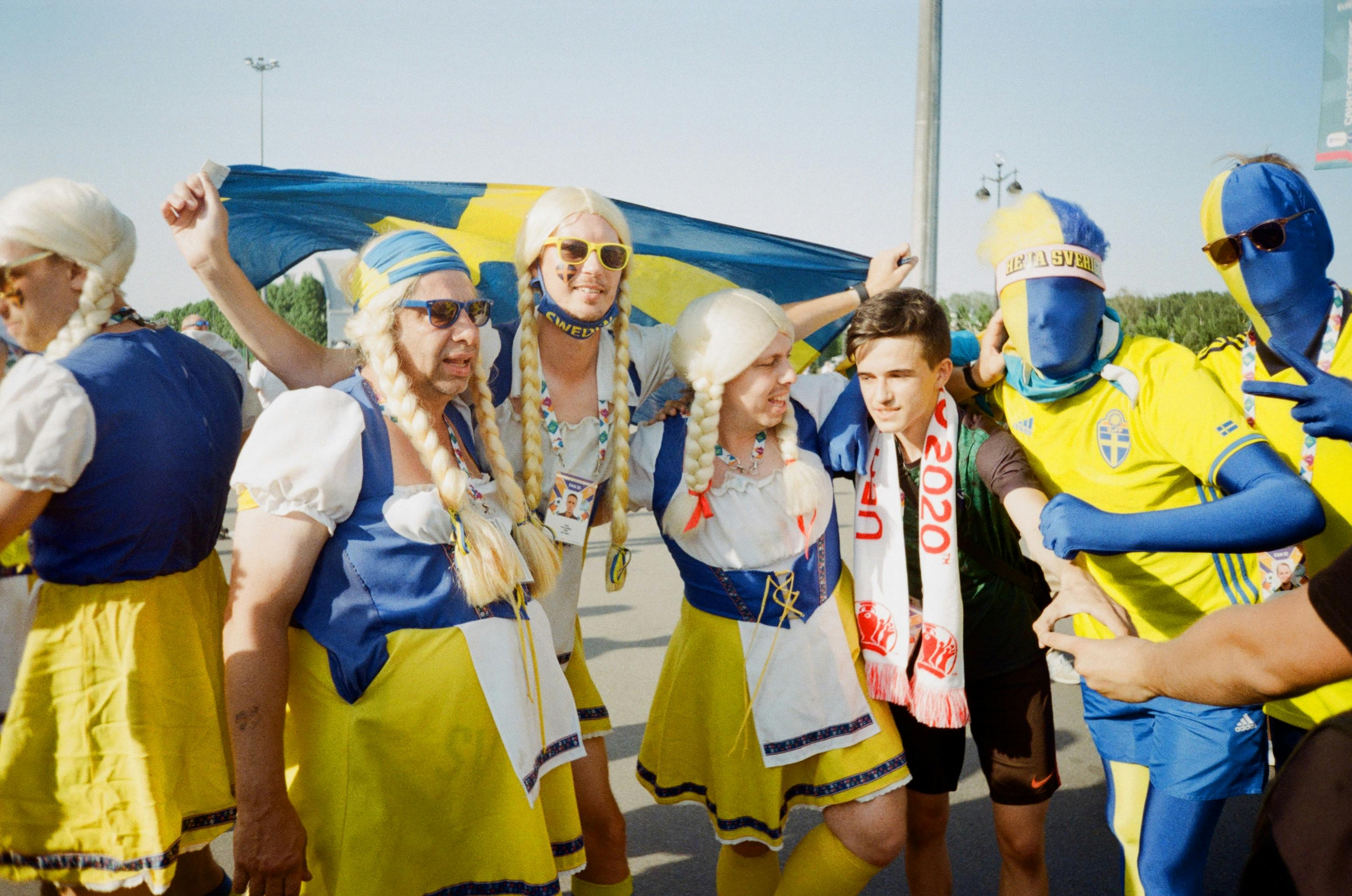 Enthusiastic Swedish fans in colorful costumes showing team spirit at an outdoor gathering.