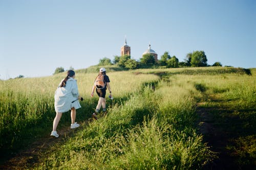 Women Walking on Green Grass of the Hill