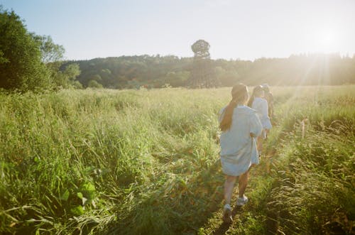 Photo of Women Walking on a Field with Green Grass