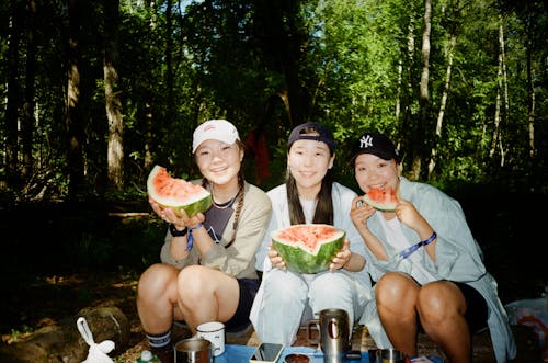 Free Photo of Tree Women Eating Watermelon while Looking at the Camera Stock Photo