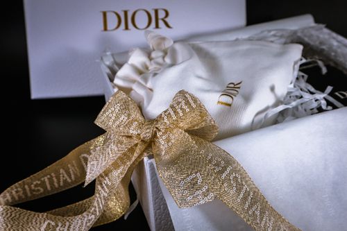 Free Luxurious Dior gift box featuring a golden sequin ribbon, exuding elegance and style. Stock Photo