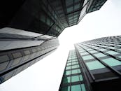 从低角度仰望现代摩天大楼，玻璃窗映出城市天际线