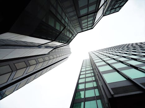 从低角度仰望现代摩天大楼，玻璃窗映出城市天际线