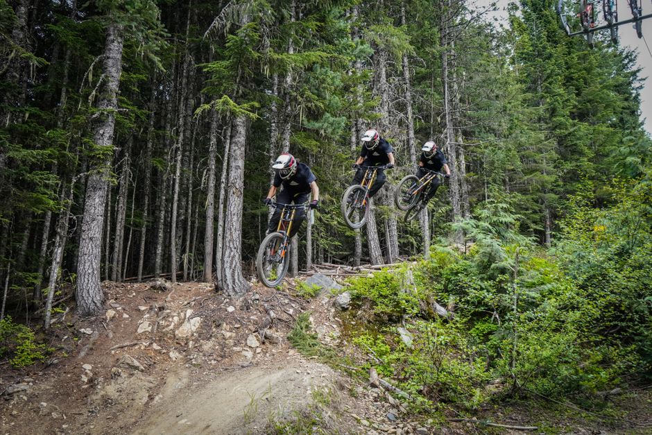 Mountain bikers performing an exciting jump on a forest trail.