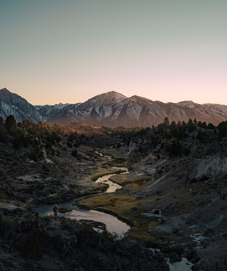 Hiker Looking At View Of River Meandering In Valley