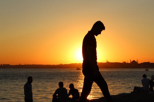 Free People by a Sea at Sunset  Stock Photo