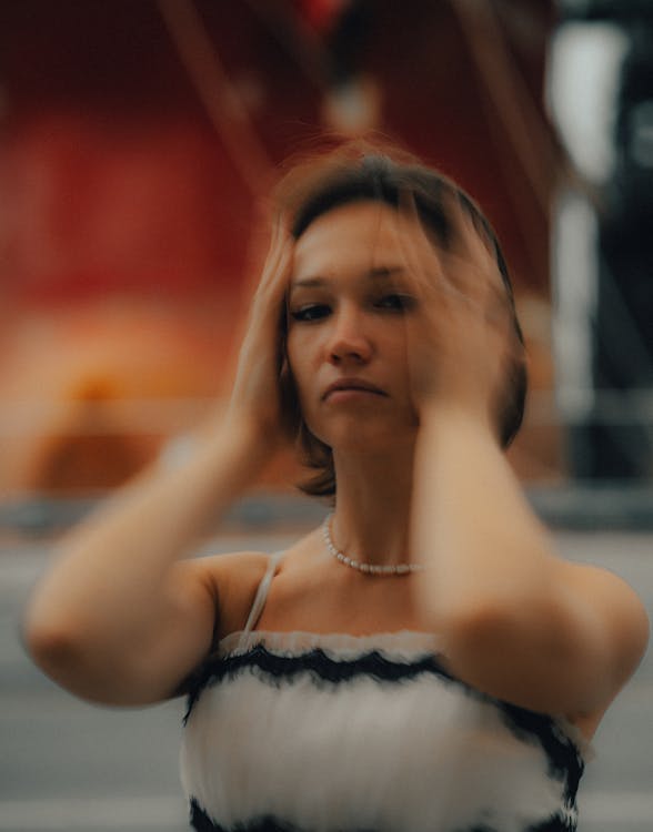 Woman in White Spaghetti Strap Top Projecting on the Camera while Holding her Head