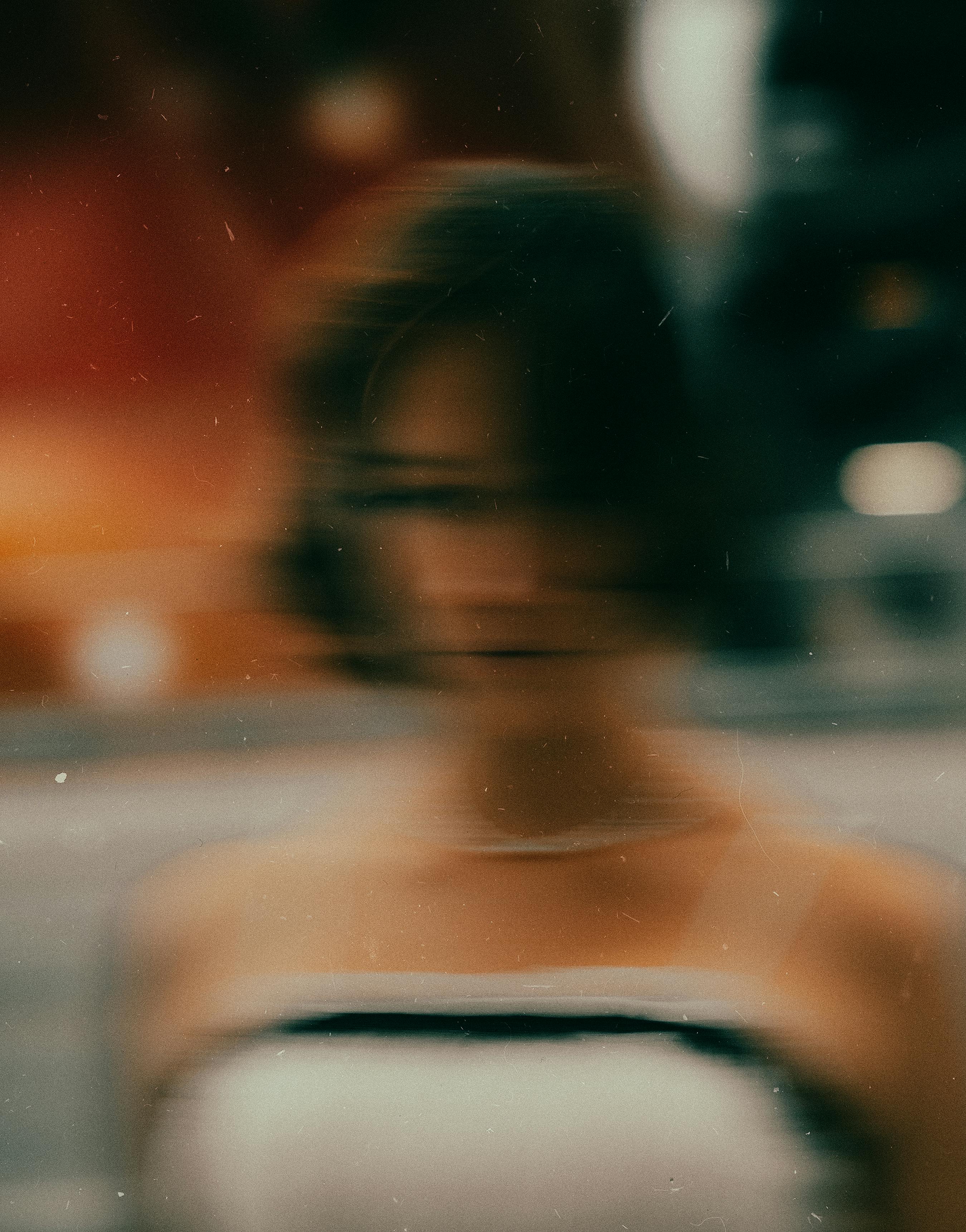 Blurred artistic close-up of a woman in formal attire, creating a dreamy, surreal effect.