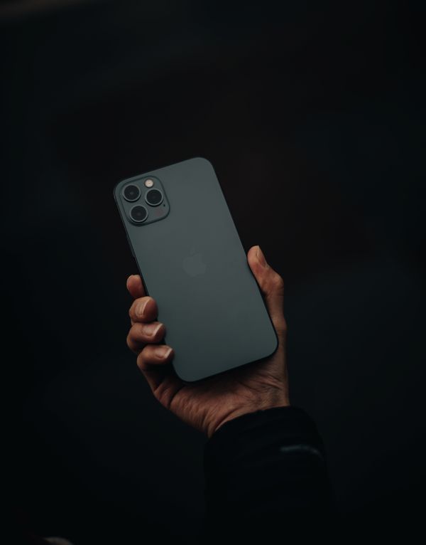A hand holding a smartphone against a black background — photo by Bekir Donmez on Pexels