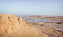 蔚蓝的天空下，宁静的沙漠景观以岩石悬崖和蜿蜒的河流为特色