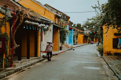 A Person Walking on Street beside Yellow Building