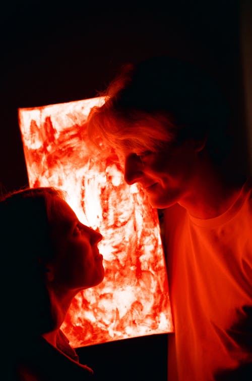 A Man and a Woman in front of Red Light Looking at Each Other