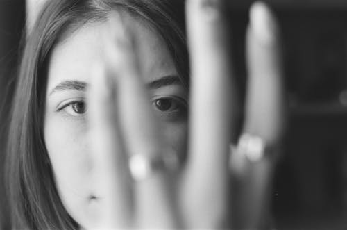 Monochrome Photo of a Woman Looking Through Her Fingers
