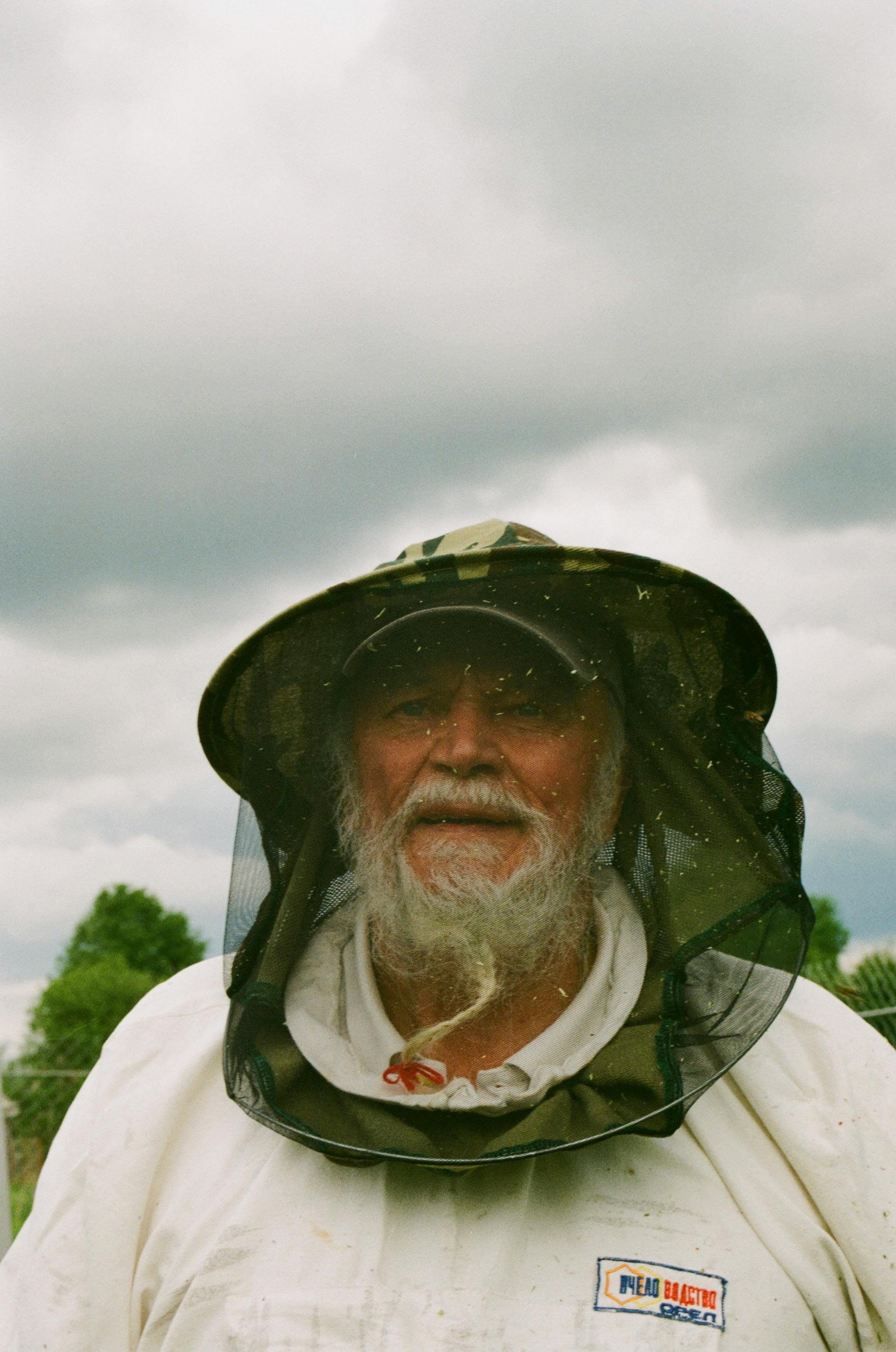 U.S. Marine Corps Veteran carefully inspecting a beehive, wearing protective gear, demonstrating focus and purpose in beekeeping
