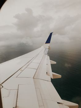 Dramatic view of airplane wing above dense clouds over Panama's coastline.