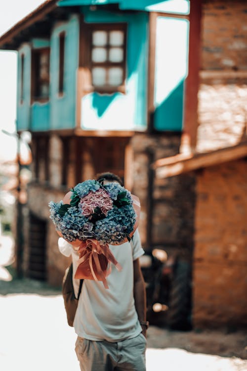 A Person in White Shirt Holding a Bouquet of Beautiful Flowers