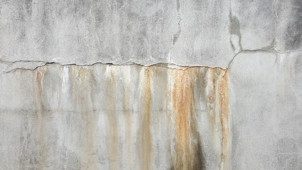 Concrete wall with rust stains running down from a horizontal crack