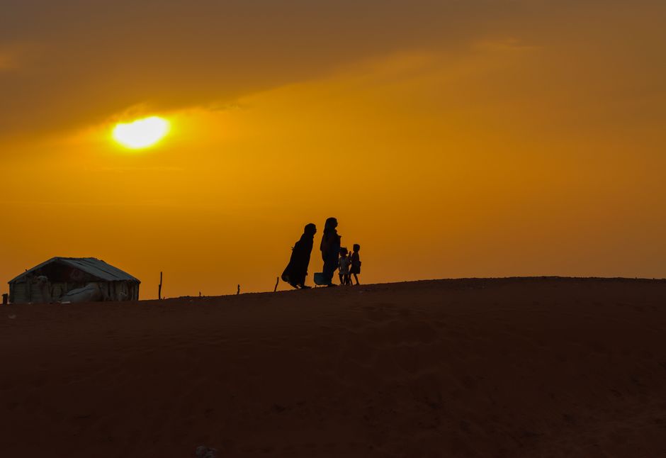 Silhouetted family walking on a dune during a golden sunset in Nouakchott.