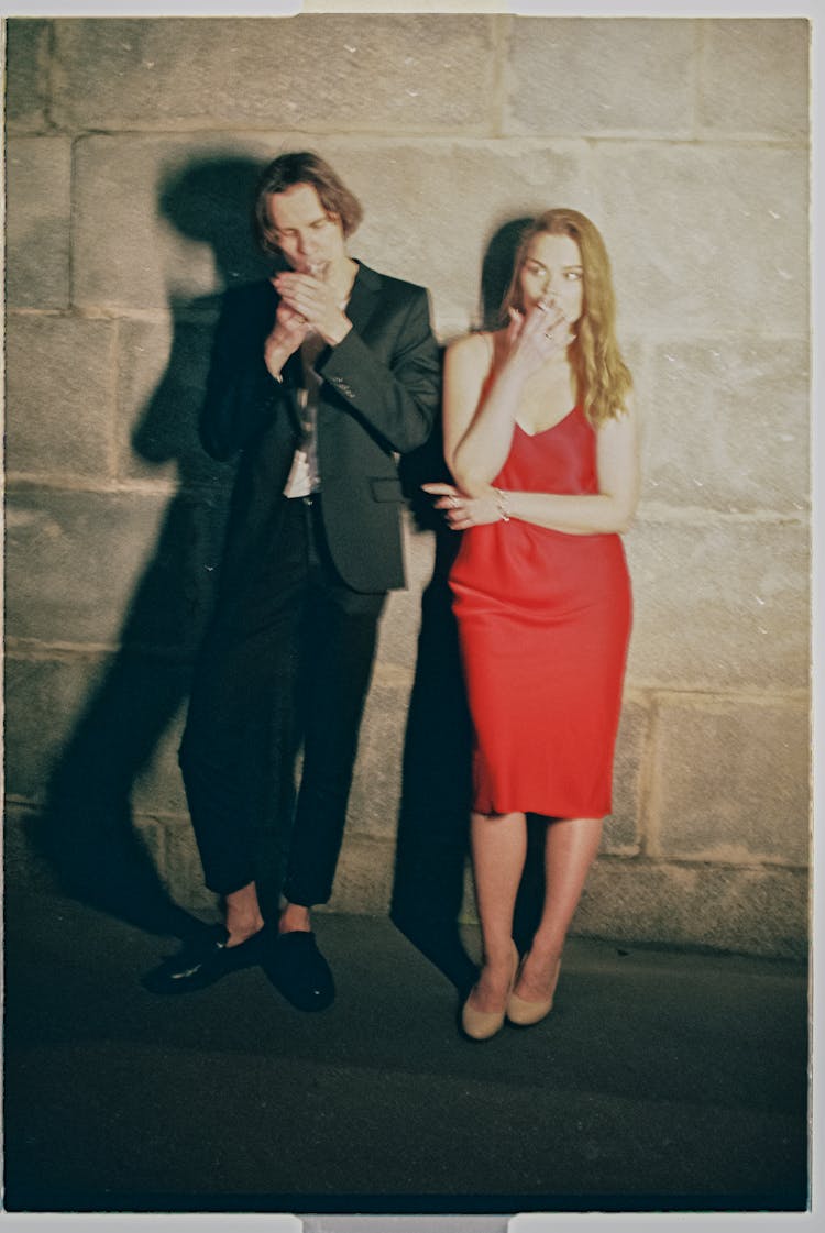 Man And Woman Smoking Cigarettes Near The Wall