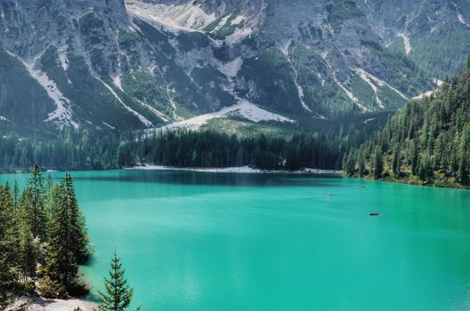 Explore this serene mountain lake with clear turquoise water and lush forests.