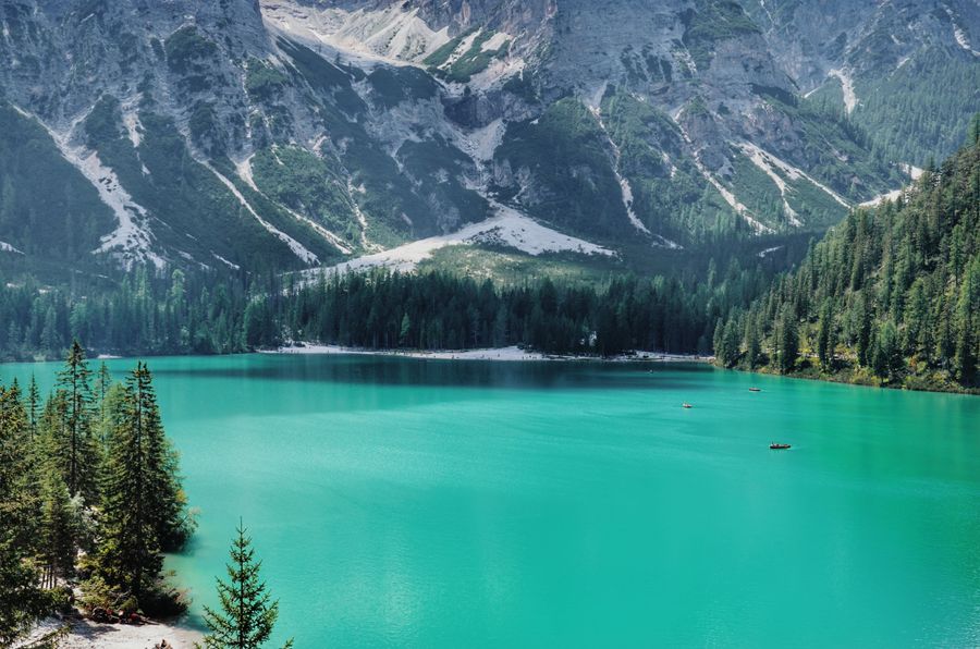 Turquoise alpine lake below a forested ridge, by photoGraph on Pexels