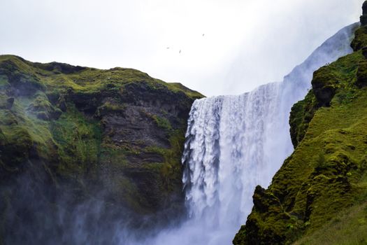 A stunning waterfall cascading over moss-covered cliffs in Iceland, showcasing nature's beauty.