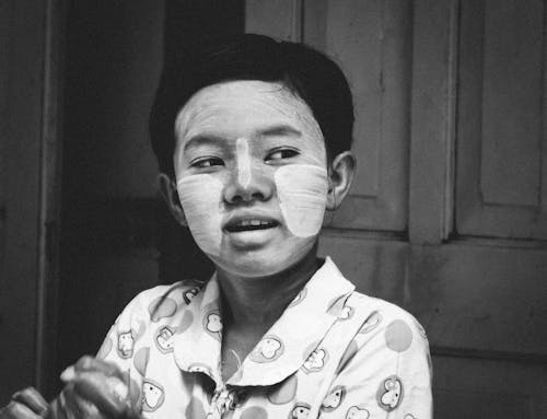 A Grayscale Photo of a Young Boy with Cream on His Face