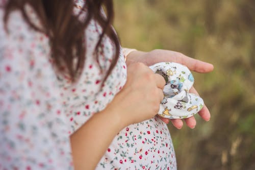 A Pregnant Woman Holding Baby Shoes