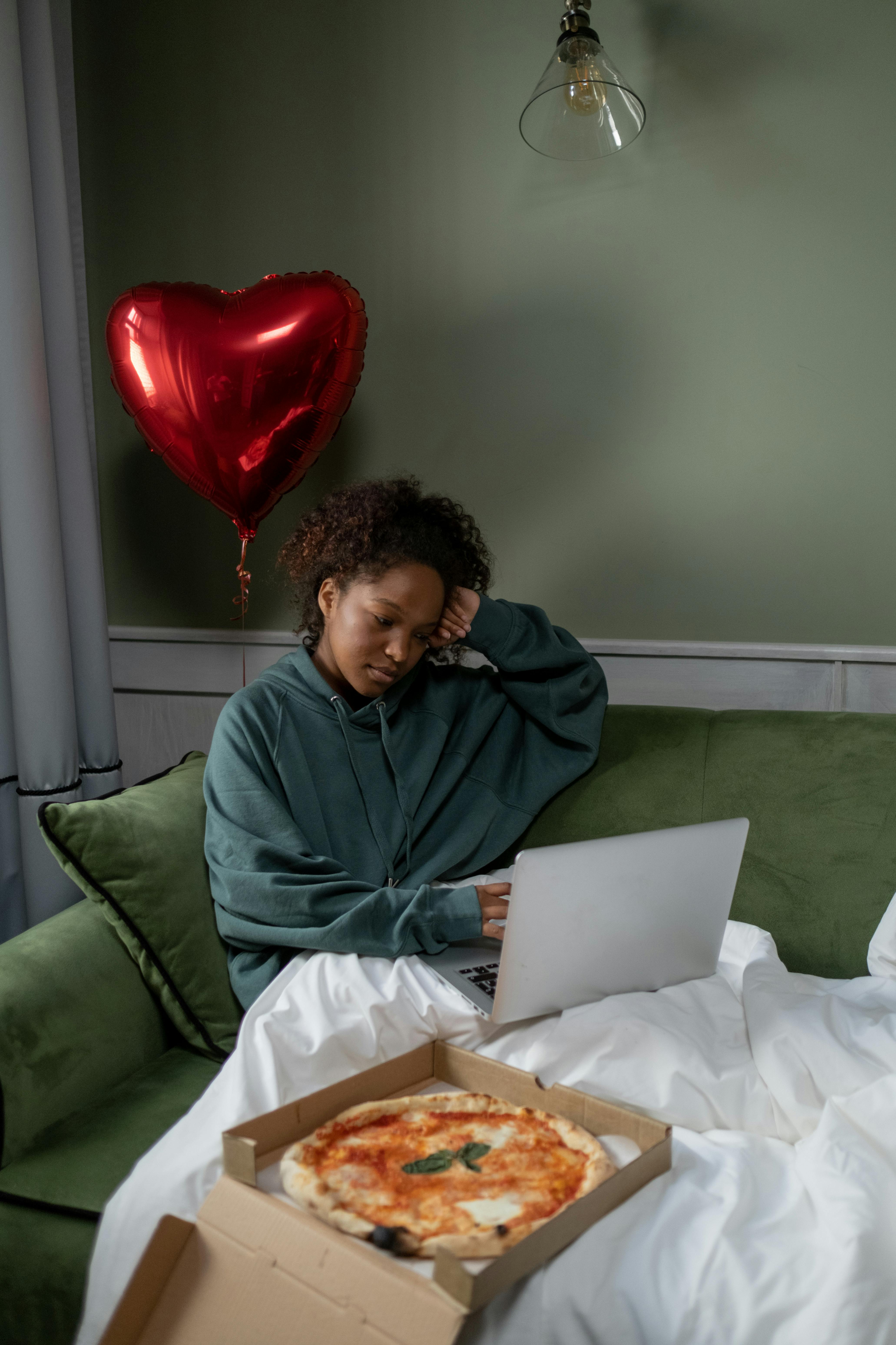 a woman sitting on the couch while watching movie on her laptop