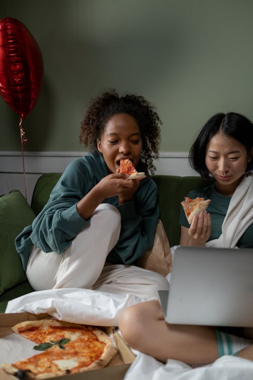 A Couple Eating Pizza while Watching a Movie on a Laptop
