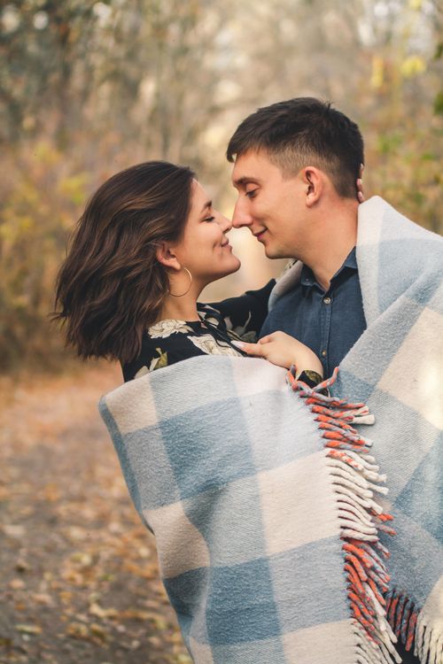 Free A loving couple wrapped in a blanket, sharing a tender moment outdoors in autumn. Stock Photo