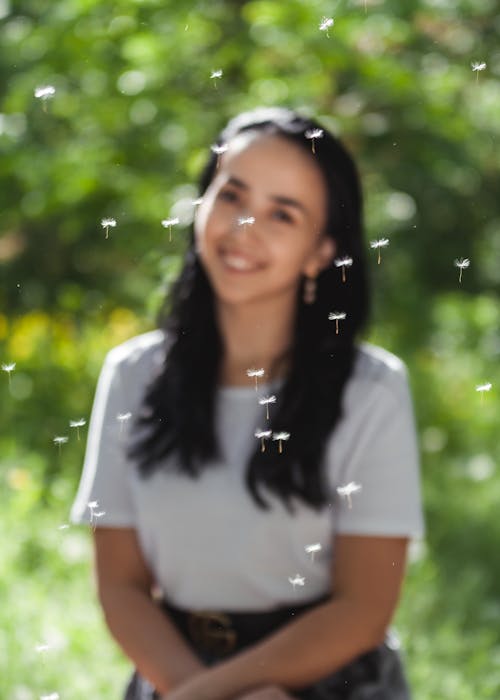 Photo of a Woman Smiling Near Dandelion Seeds