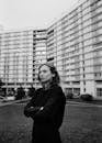 Woman Standing with Folded Hands Before Huge Residential Building