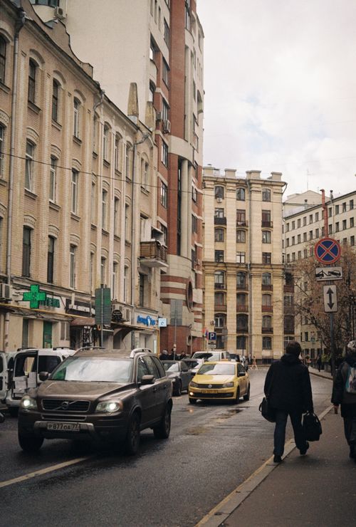 Free A city street scene with buildings, cars, and people walking on the sidewalk. Stock Photo