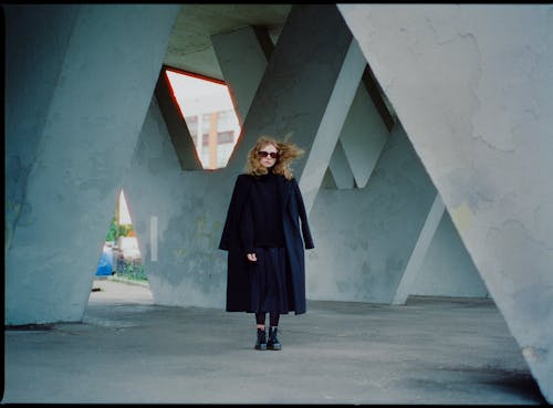 Redhead Woman with Long Flying Hair Standing under Concrete Structure