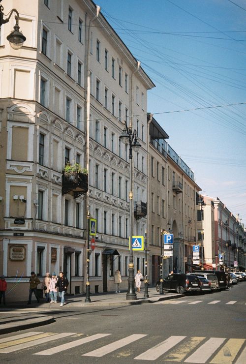 Free City street with pedestrians, cars, and historic buildings under clear blue sky. Stock Photo