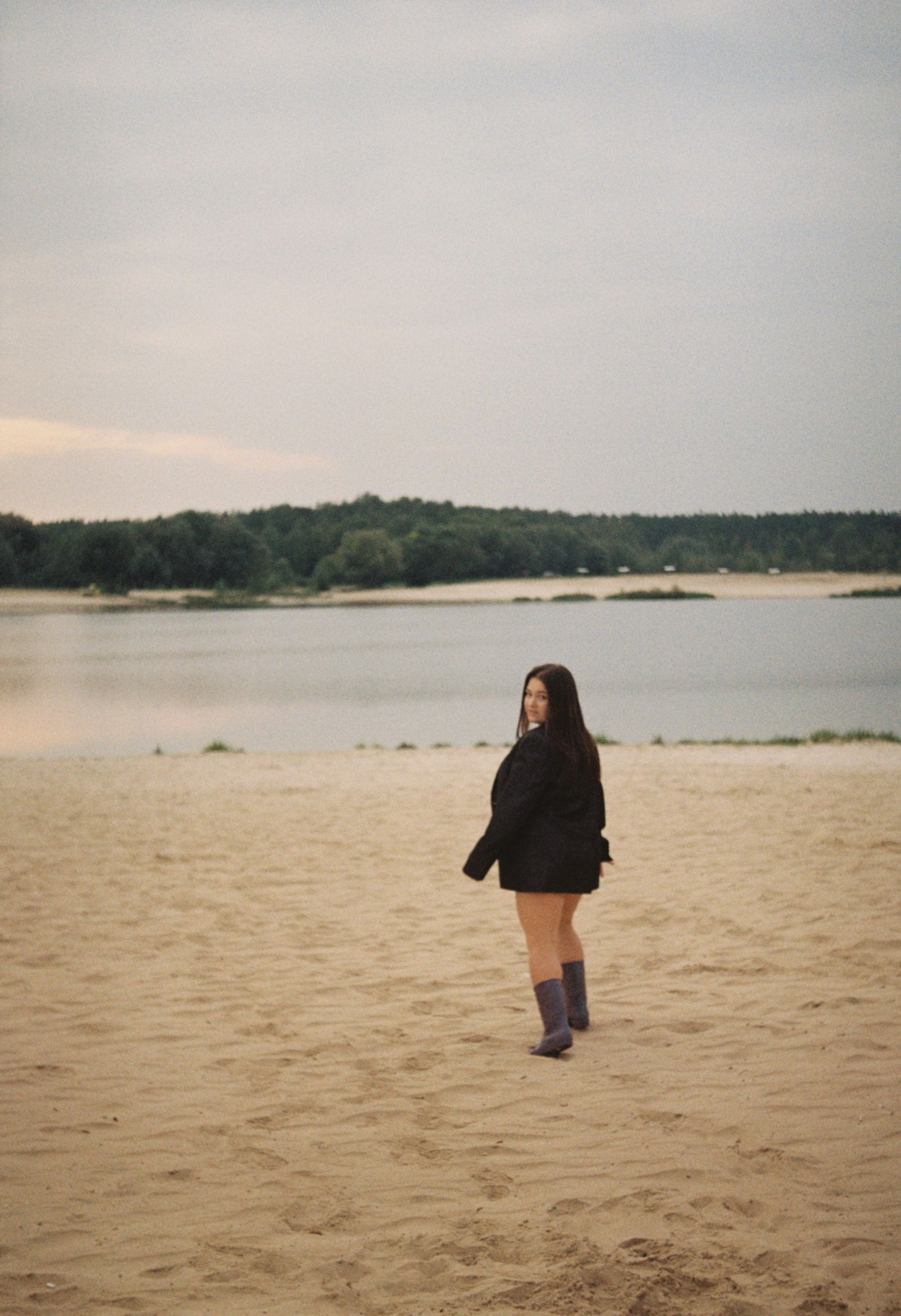 Woman in Black Jacket Walking on Brown Sand · Free Stock Photo