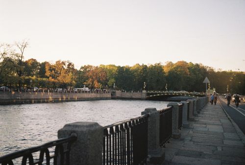 Free Beautiful riverside view with people walking at dusk, capturing autumn colors. Stock Photo