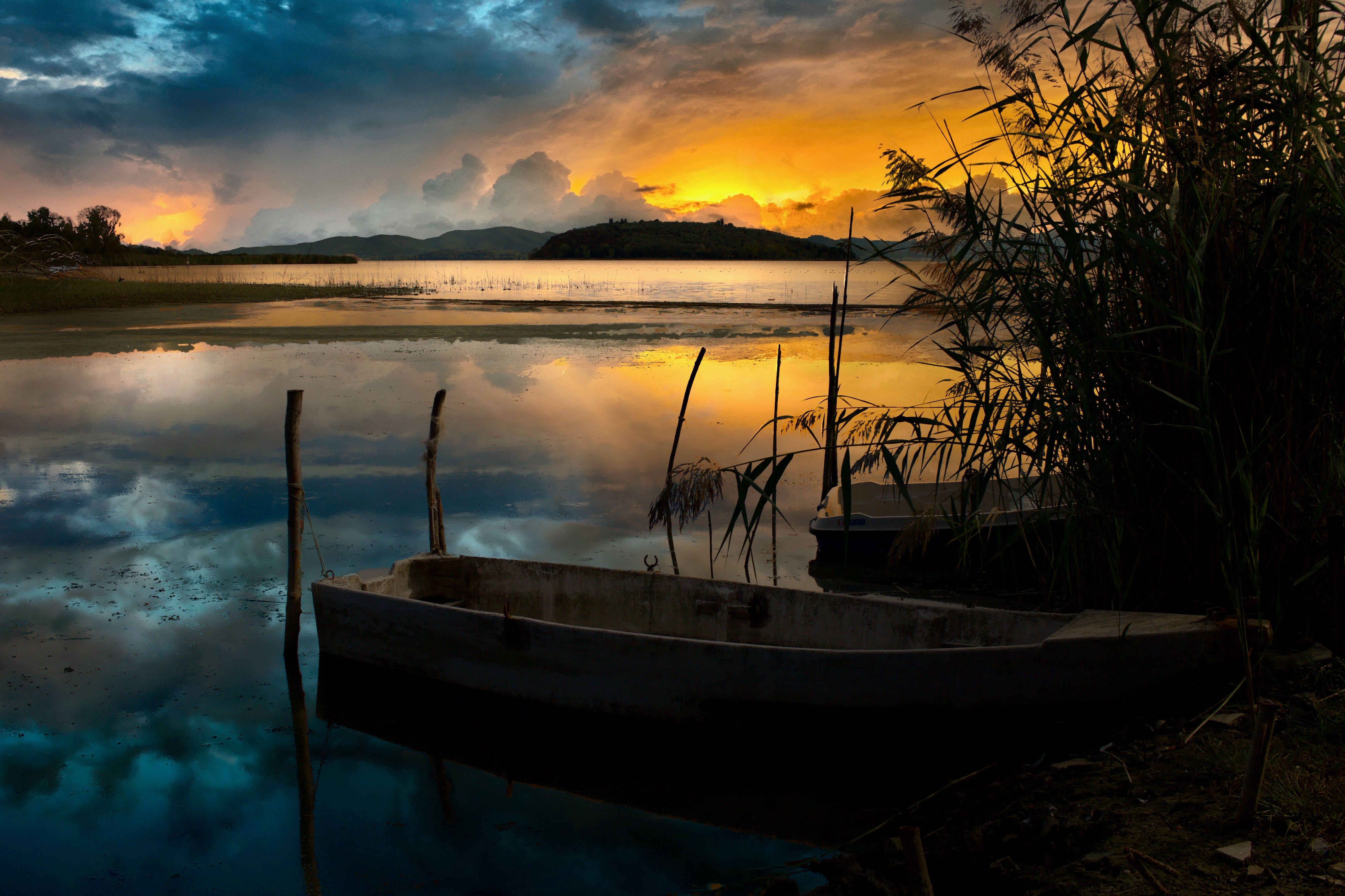 Serene sunset at Lake Trasimeno with wooden boats and vibrant reflections.