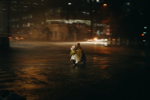 Motorcycle delivery in a rainy city, captured at night, highlighting urban life and transportation.